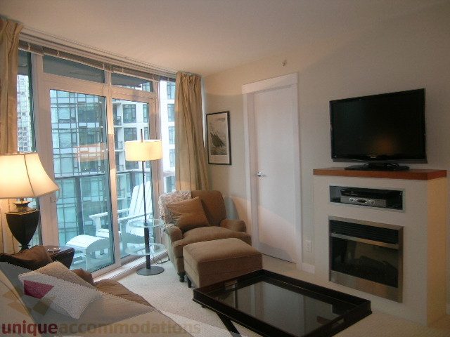 Bright living room with large windows, city view, and modern furniture. - 907 - 1189 Melville Street, Vancouver Downtown