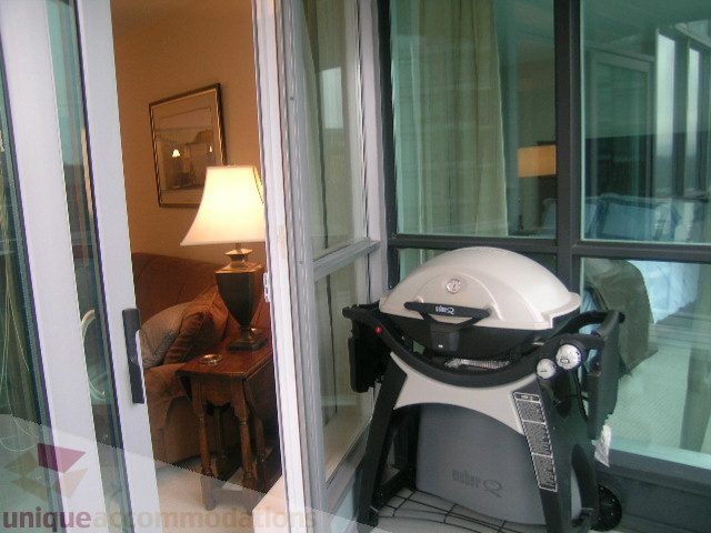 Bright living room with large windows and a modern treadmill. - 907 - 1189 Melville Street, Vancouver Downtown