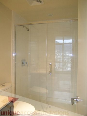 Modern bathroom with glass shower, sleek countertop, and city view. - 1903 - 1320 Chesterfield Street, North Vancouver
