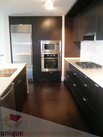 Modern kitchen with sleek black cabinets, stainless steel appliances, and dark hardwood floors. - 1903 - 1320 Chesterfield Street, North Vancouver