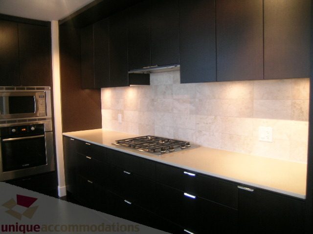 Modern kitchen with sleek black cabinets, granite countertops, and a gas stove. - 1903 - 1320 Chesterfield Street, North Vancouver