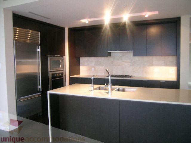 Modern kitchen with sleek black cabinets, stainless steel appliances, and a large island. - 1903 - 1320 Chesterfield Street, North Vancouver