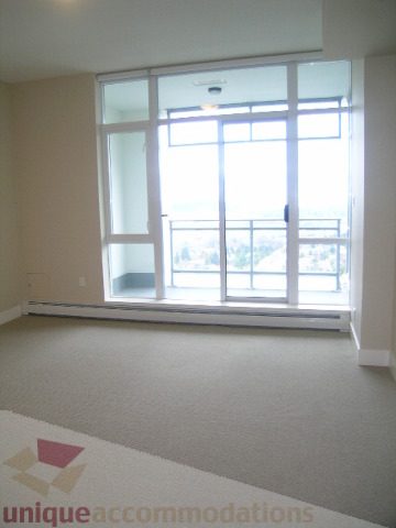 Spacious living room with large windows offering a city view and a cozy corner seating area. - 1903 - 1320 Chesterfield Street, North Vancouver
