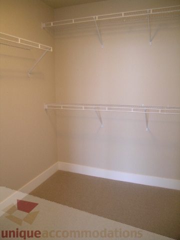 Spacious walk-in closet with white shelving and carpeted floor. - 1903 - 1320 Chesterfield Street, North Vancouver