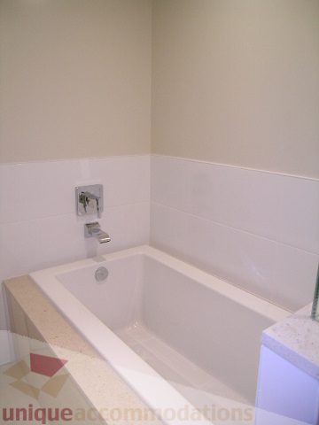Modern bathroom with white bathtub, marble countertop, and neutral walls. - 1903 - 1320 Chesterfield Street, North Vancouver