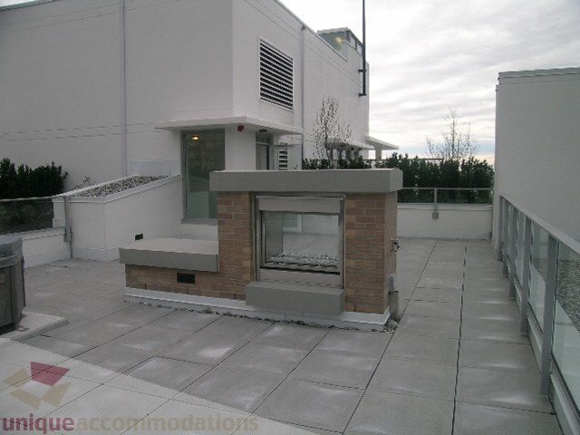 Spacious rooftop patio with modern grill and glass railings, perfect for entertaining. - 1903 - 1320 Chesterfield Street, North Vancouver