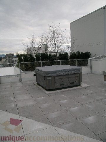 Spacious rooftop patio with modern tile flooring, hot tub, and city views. - 1903 - 1320 Chesterfield Street, North Vancouver