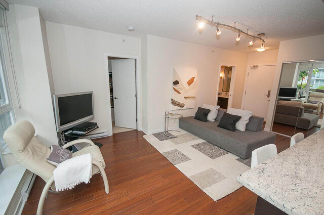 Spacious living room with hardwood floors, modern furniture, and a large abstract wall art piece. - 903 - 821 Cambie Street, Vancouver Downtown