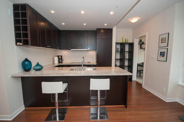 Modern kitchen with granite countertops, dark wood cabinets, and a breakfast bar. - 903 - 821 Cambie Street, Vancouver Downtown