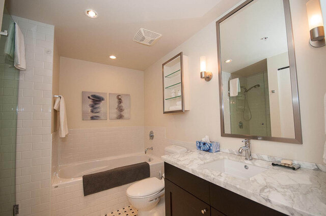 Spacious bathroom with marble countertops and a large mirror, featuring a modern design and ample storage.