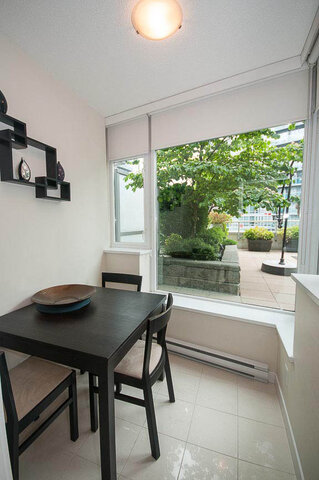 Spacious dining area with a black table, chairs, and a view of lush greenery outside. - 903 - 821 Cambie Street, Vancouver Downtown