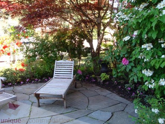 Spacious patio with wooden lounge chairs and lush greenery, perfect for relaxation. - 1330 Sinclair Street, West Vancouver