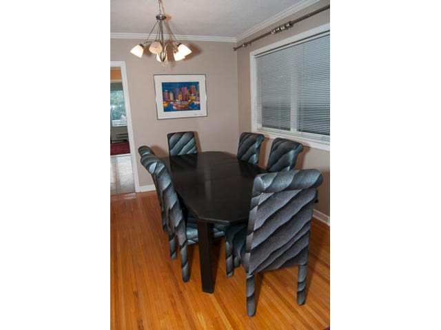 Furnished dining room with hardwood floors and a cityscape painting. - 5680 Marine Drive, West Vancouver