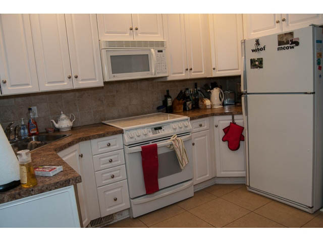 Bright kitchen with granite countertops, white cabinets, and a red oven mitt. - 5680 Marine Drive, West Vancouver