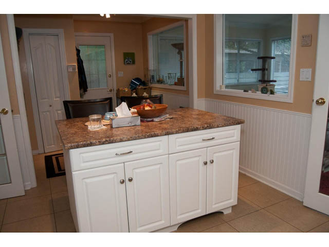 Bright kitchen with granite countertops and white cabinets, leading to a dining area. - 5680 Marine Drive, West Vancouver