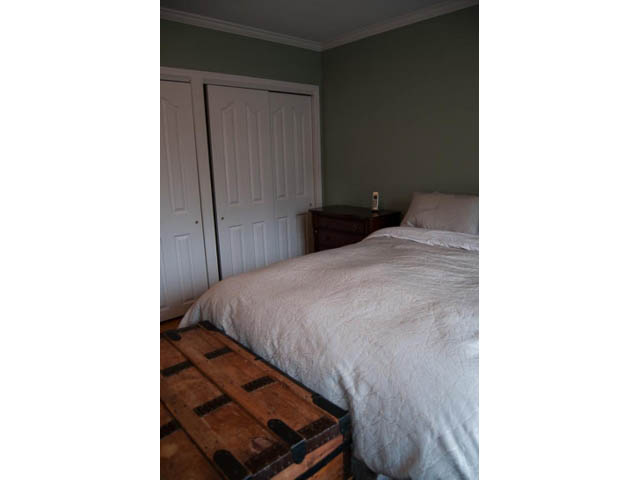 Furnished bedroom with white bedding and wooden furniture. - 5680 Marine Drive, West Vancouver