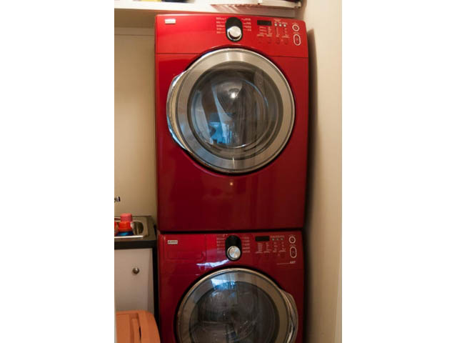 Bright laundry room with red front-load washer and dryer, clean and organized. - 5680 Marine Drive, West Vancouver