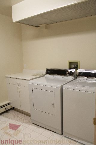Bright laundry room with white countertops and a compact washer/dryer setup. - 900 - 1919 Beach Ave, Vancouver Downtown