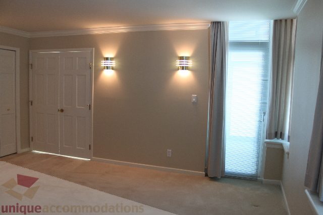 Bright living room with wall sconces and large window, carpeted floor. - 900 - 1919 Beach Ave, Vancouver Downtown