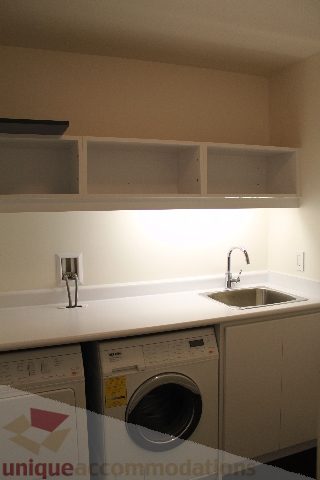 Bright laundry room with white countertops and a sink, featuring a washing machine and dryer. - 2407 - 1011 West Cordova Street, Vancouver Downtown
