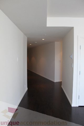 Narrow hallway leading to a door, dark wood flooring, white walls. - 2407 - 1011 West Cordova Street, Vancouver Downtown