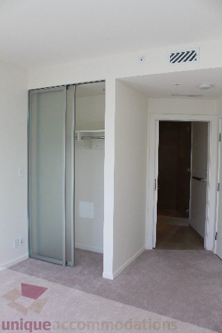 Spacious bedroom with sliding closet doors and carpeted floor. - 2407 - 1011 West Cordova Street, Vancouver Downtown