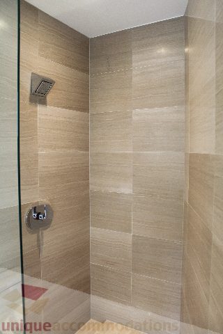 Modern shower with glass door and beige tiles. - 2407 - 1011 West Cordova Street, Vancouver Downtown