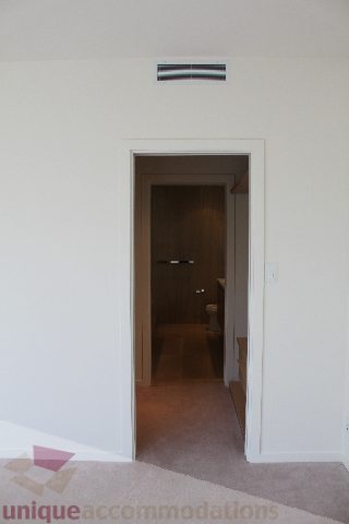 Furnished hallway leading to a bathroom with wooden door and carpeted floor. - 2407 - 1011 West Cordova Street, Vancouver Downtown