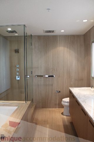 Modern bathroom with glass shower, wooden walls, and marble countertops. - 2407 - 1011 West Cordova Street, Vancouver Downtown