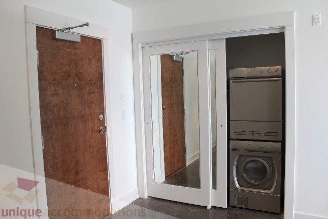 Modern kitchen with stainless steel appliances and dark wood cabinets. - 301 - 650 Evergreen Place, North Vancouver
