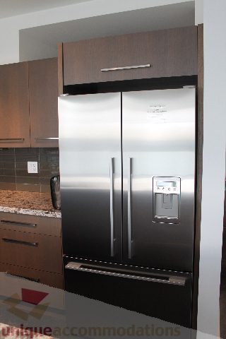 Modern kitchen with stainless steel appliances, granite countertops, and sleek cabinetry. - 301 - 650 Evergreen Place, North Vancouver