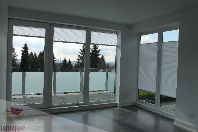 Spacious living room with large windows offering a stunning city view. - 301 - 650 Evergreen Place, North Vancouver