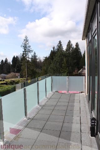 Spacious balcony with glass railings and a serene forest view. - 301 - 650 Evergreen Place, North Vancouver