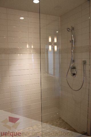 Spacious bathroom with modern glass shower, sleek fixtures, and white tile walls. - 301 - 650 Evergreen Place, North Vancouver