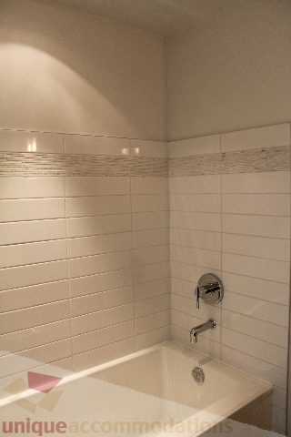 Spacious bathroom with white tiled walls and modern fixtures, perfect for a cozy stay. - 301 - 650 Evergreen Place, North Vancouver