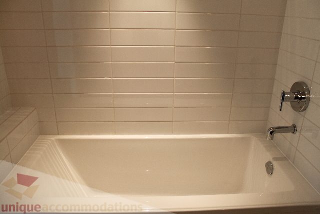 Spacious bathroom with modern sink, sleek countertop, and tiled walls. - 301 - 650 Evergreen Place, North Vancouver