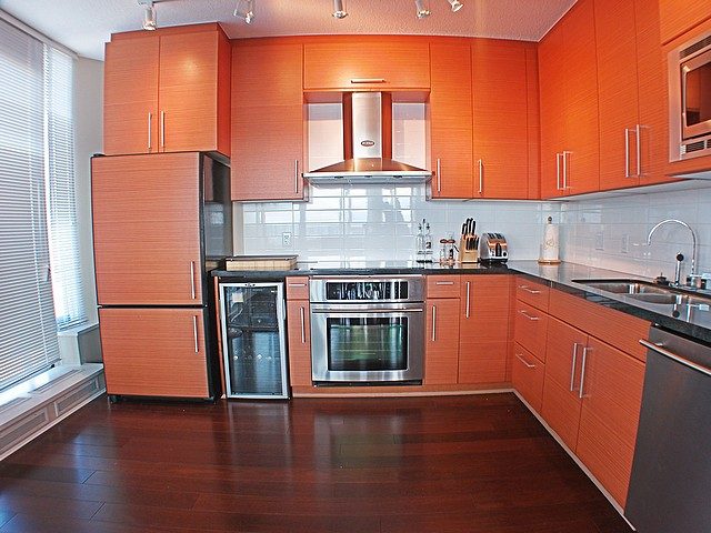 Bright kitchen with orange cabinets, stainless steel appliances, and hardwood floors. - 3705 - 689 Abbott Street, Vancouver Downtown