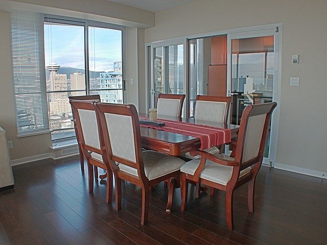 Dining area with hardwood floors, city view, and wooden chairs. - 3705 - 689 Abbott Street, Vancouver Downtown