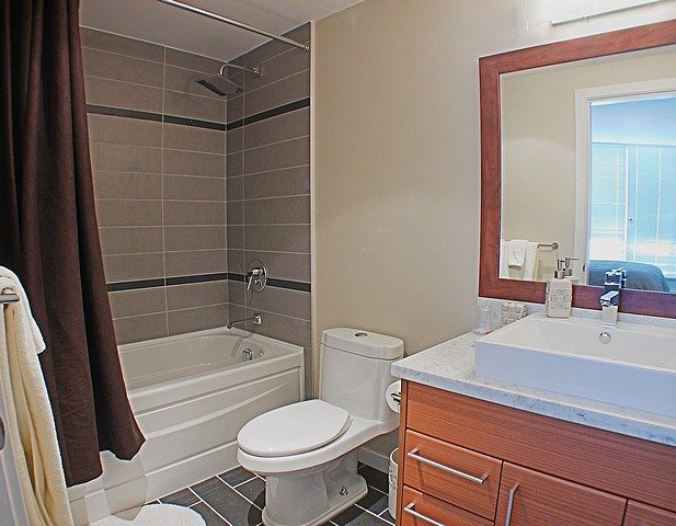 Furnished bathroom with wooden vanity, marble countertop, and city view. - 3705 - 689 Abbott Street, Vancouver Downtown