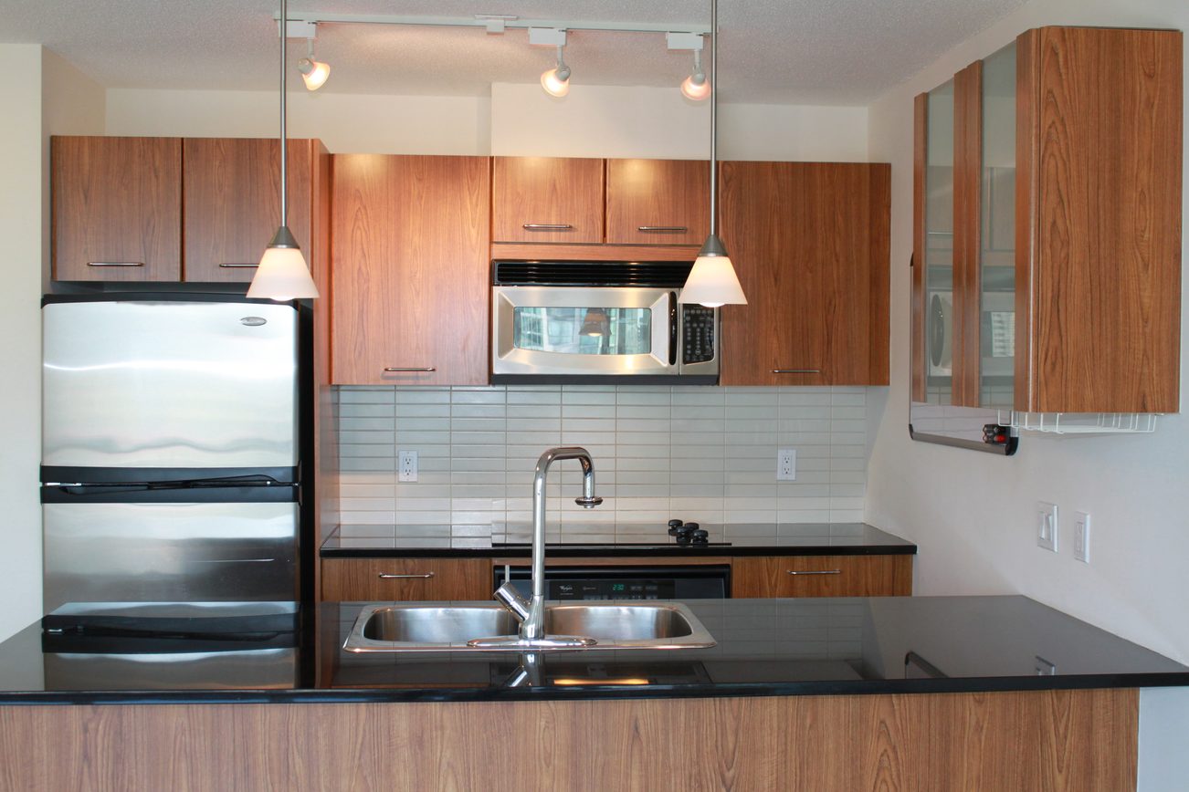 Bright kitchen with modern wood cabinets, stainless steel appliances, and black countertops. - 2001 - 1199 Seymour, Vancouver Downtown