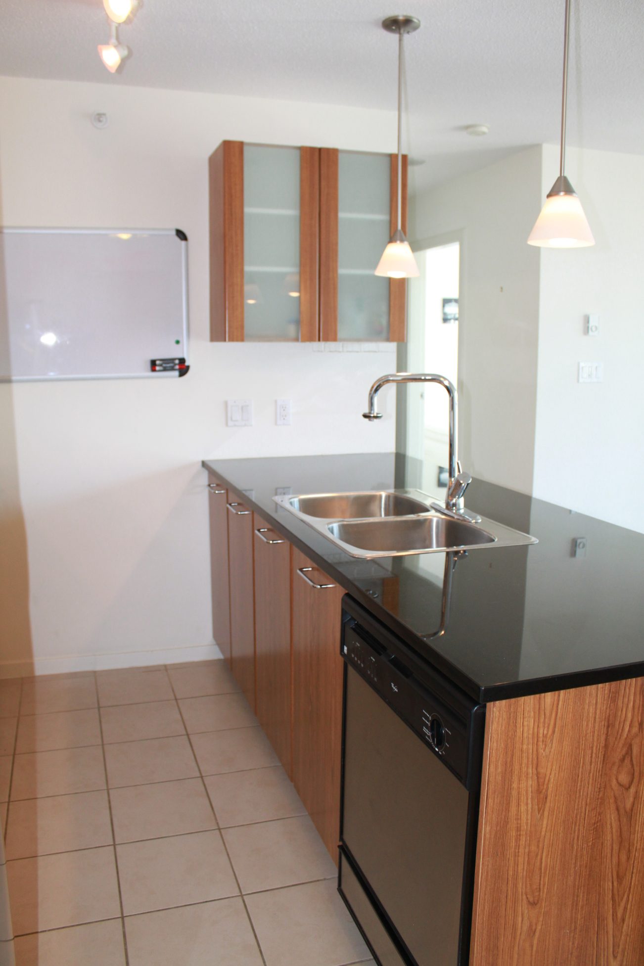 Bright kitchen with modern black countertops, wooden cabinets, and pendant lights. - 2001 - 1199 Seymour, Vancouver Downtown