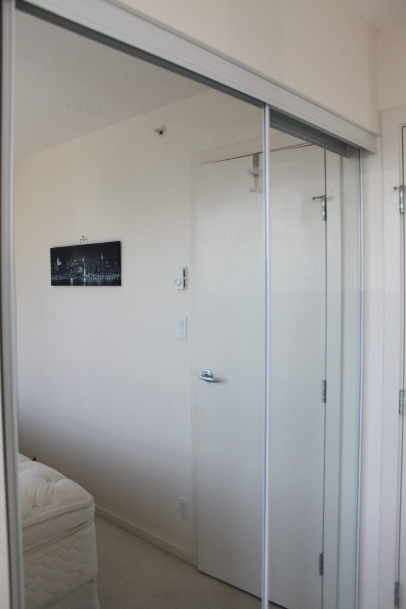 Bright bedroom with sliding closet doors and a cityscape wall art. - 2001 - 1199 Seymour, Vancouver Downtown