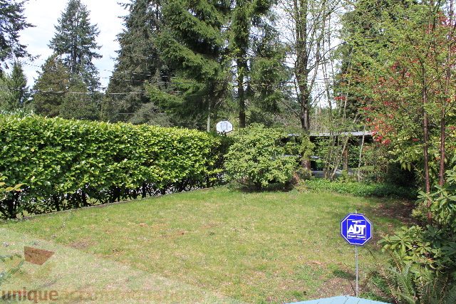 Furnished garden with lush greenery and a blue ADT security sign. - 2156 Cortell Ave, North Vancouver