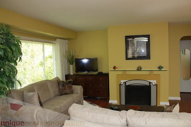 Living room with yellow walls, large window, and a comfortable couch. - 2156 Cortell Ave, North Vancouver