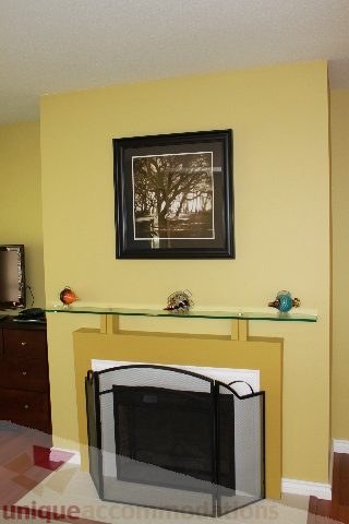 Living room with glass-topped fireplace, yellow walls, and framed artwork. - 2156 Cortell Ave, North Vancouver