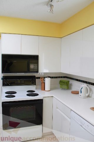 Bright kitchen with white cabinets, black appliances, and granite countertops. - 2156 Cortell Ave, North Vancouver
