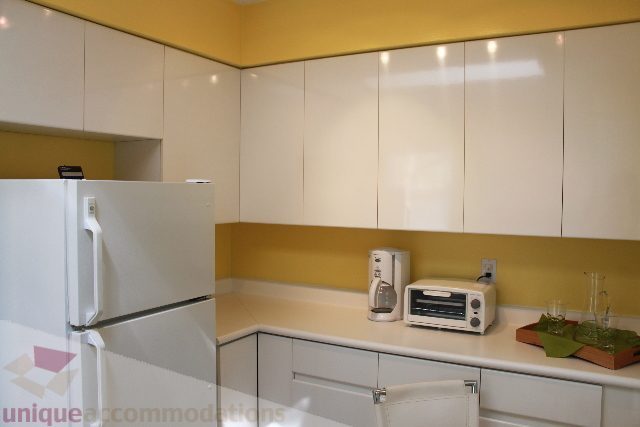 Bright kitchen with white cabinets, yellow walls, and modern appliances. - 2156 Cortell Ave, North Vancouver