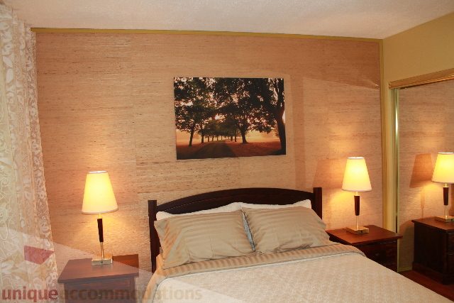 Furnished bedroom with cozy lighting and a scenic wall art piece. - 2156 Cortell Ave, North Vancouver