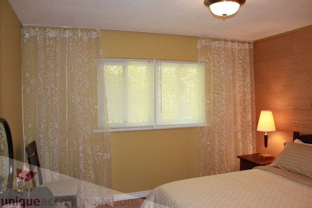 Bright bedroom with patterned curtains and a cozy ambiance. - 2156 Cortell Ave, North Vancouver