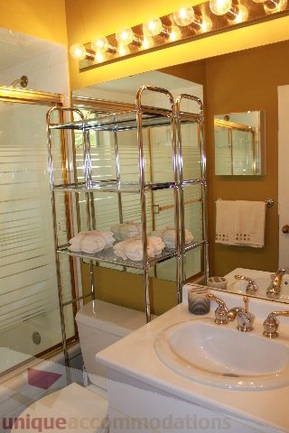 Bathroom with modern sink, chrome shelves, and warm lighting. - 2156 Cortell Ave, North Vancouver